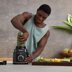 Man using Ninja Detect Power Blender Pro TB301ME single-serve cup to blend a green smoothie