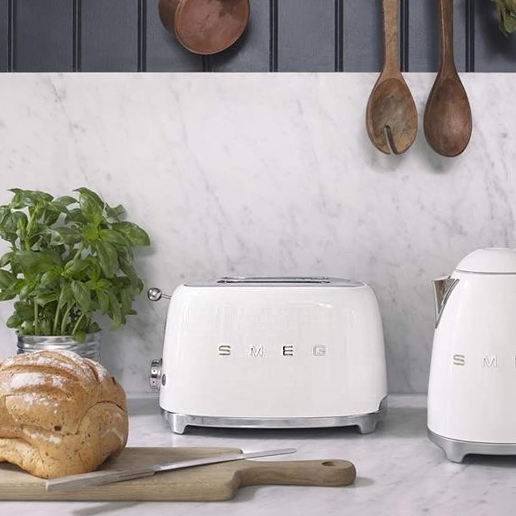 Smeg TSF01CREU Cream toaster styled on a marble kitchen counter next to matching kettle and fresh bread